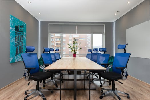 Contemporary office space with blue chairs, table, and motivational quote on the wall.