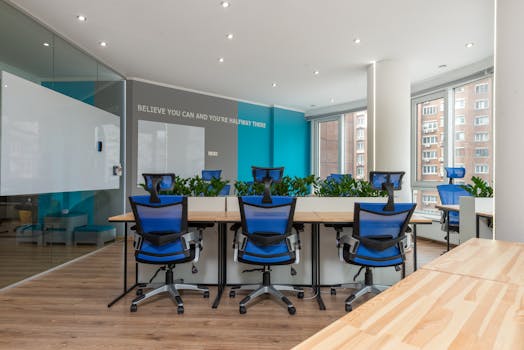 Contemporary office interior with blue chairs and greenery, promoting creativity and efficiency.