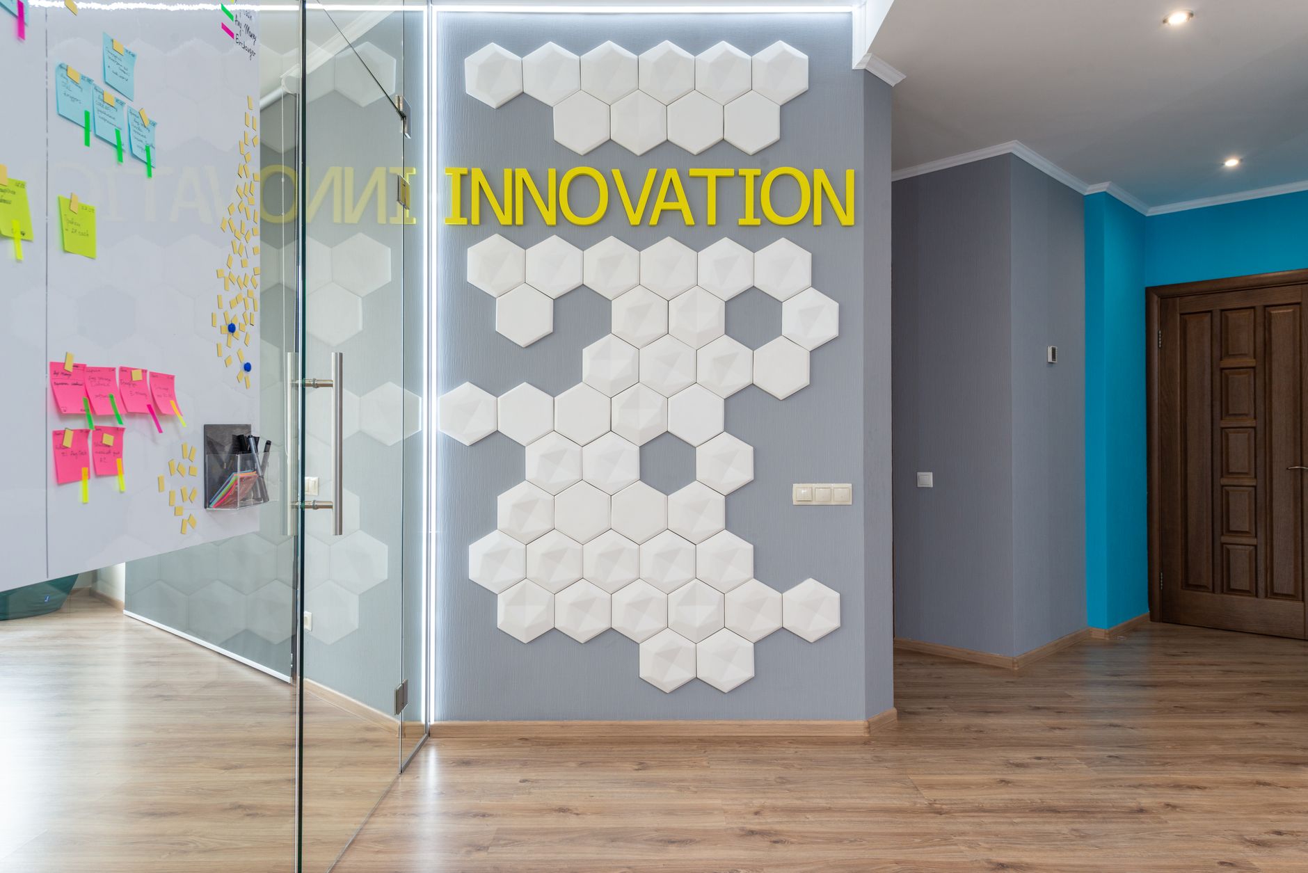 Geometric decoration on wall with Innovation inscription near glass door of conference room with colorful stickers in hallway of office building