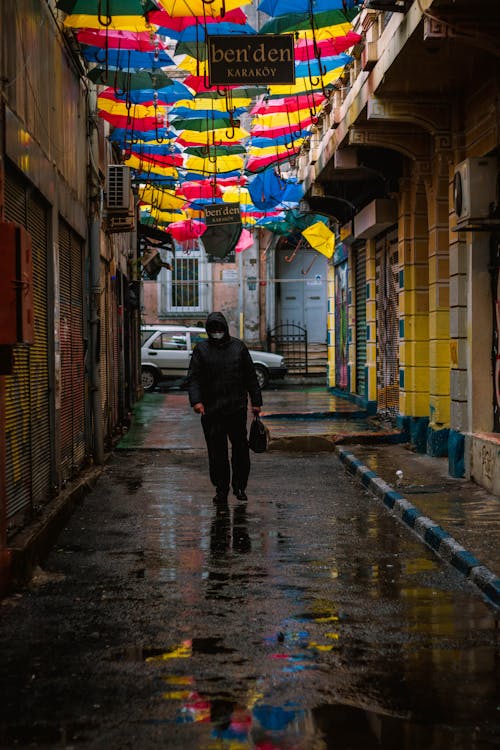 A Man in Black Jacket Walking on Street