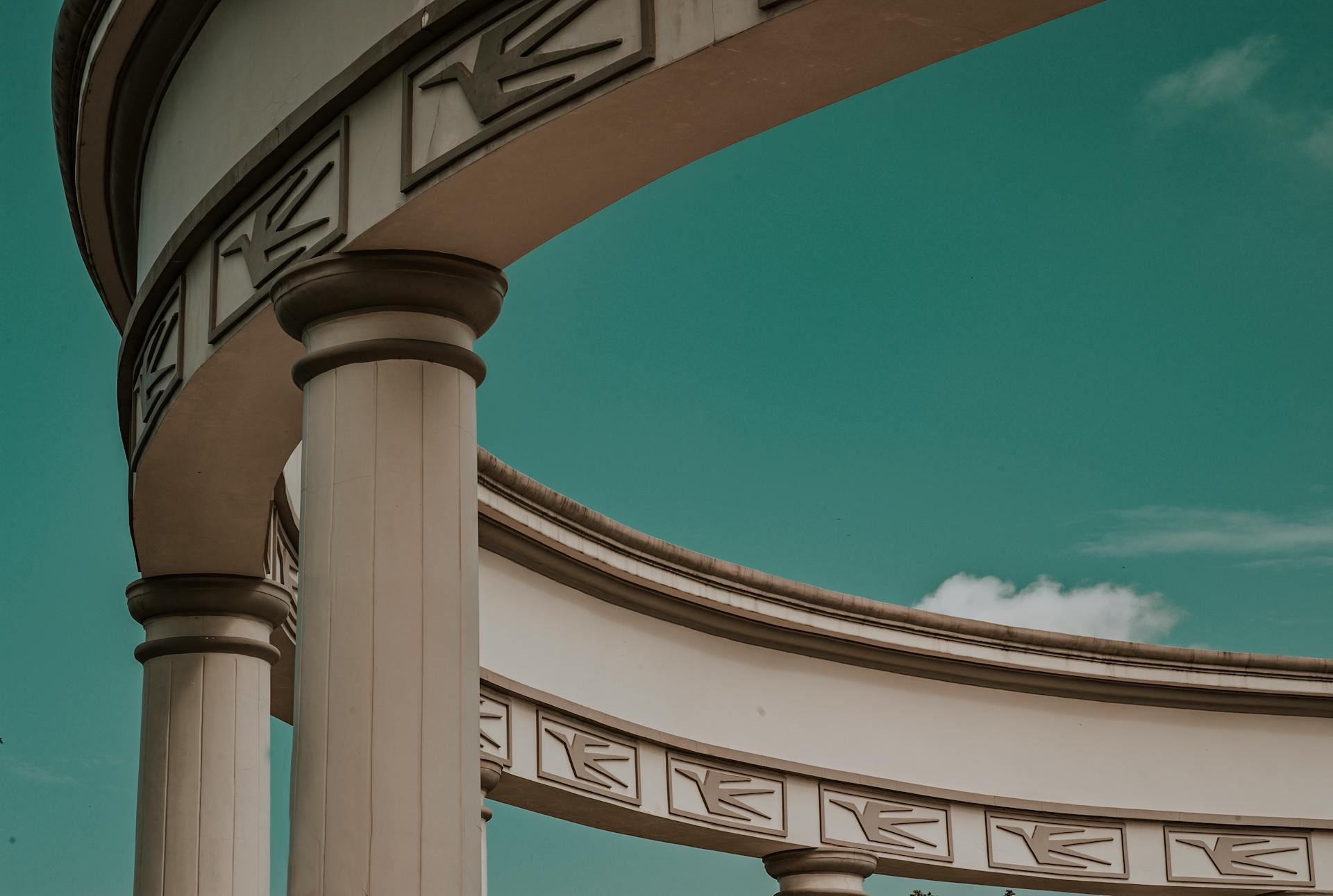 Captivating architectural columns with elegant curves against a beautiful blue sky.