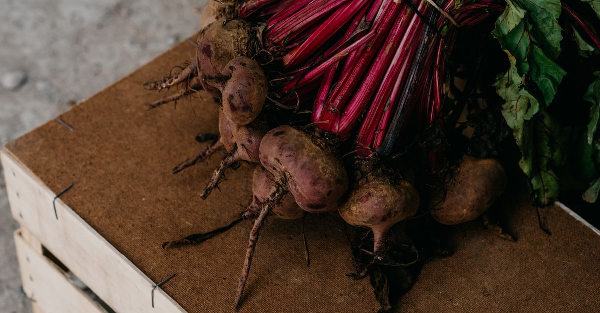 A bunch of fresh organic beetroots with leaves on a rustic wooden crate, showcasing root vegetables. - Evidence evidence guide for beetroot exercise recovery meta-analysis