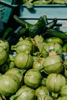 Pile of fresh round zucchinis at a farmers market, showcasing organic produce.