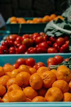 Fresh organic oranges and tomatoes at a local farmers market, highlighting healthy eating.