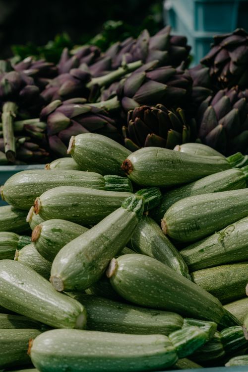 Free Close-up of fresh zucchinis and artichokes at a market stall. Stock Photo