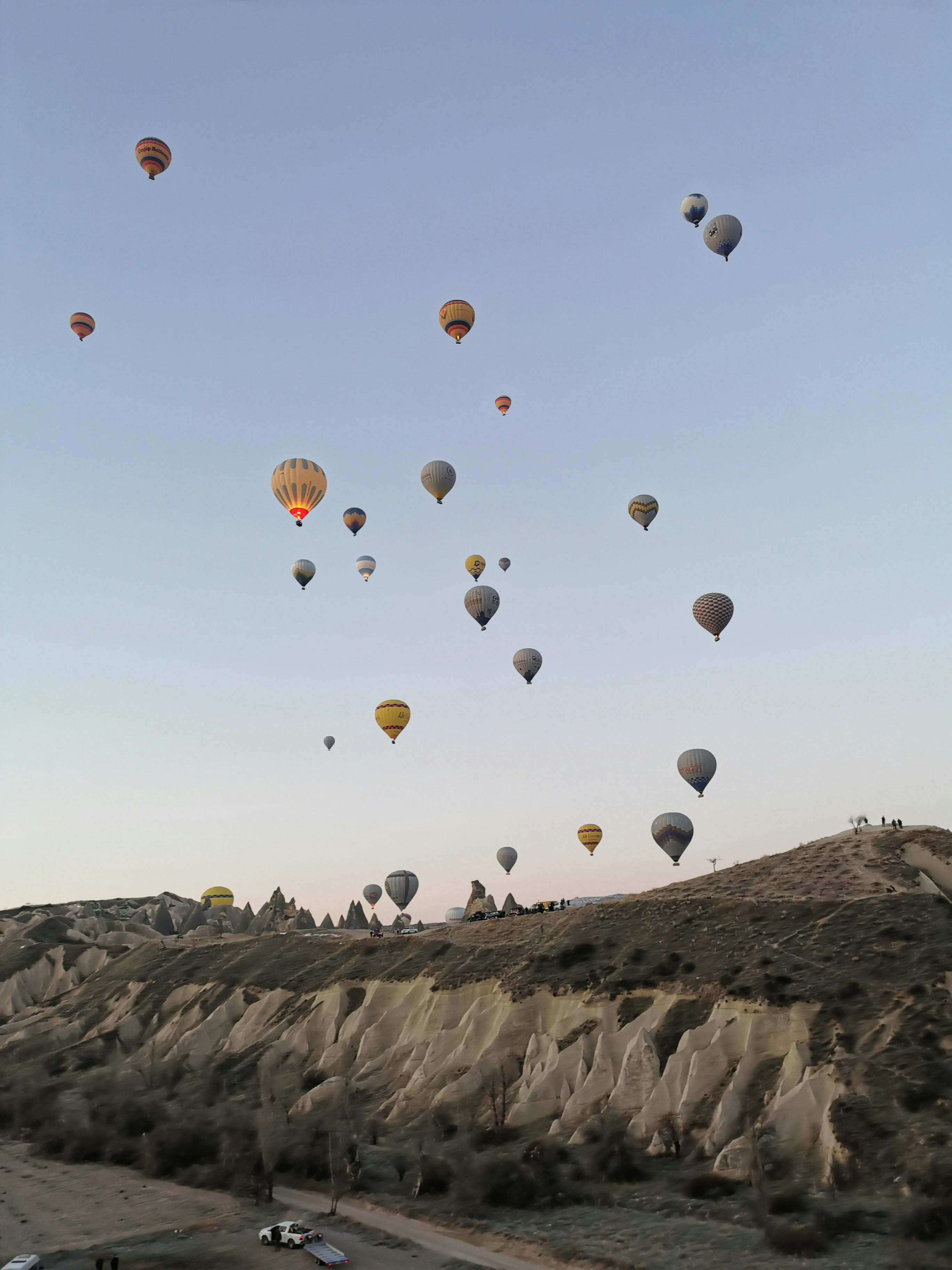 Free A breathtaking view of colorful hot air balloons floating over the rocky terrain of Cappadocia at sunrise. Stock Photo