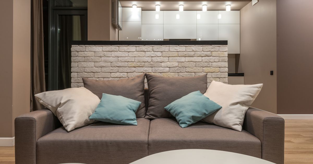 Salon moderne avec un canapé gris confortable et des coussins élégants sous un éclairage chaleureux.