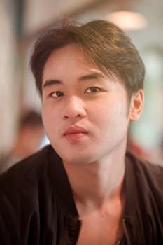 柔和的灯光下，一名年轻人的特写肖像捕捉到他深思熟虑的表情