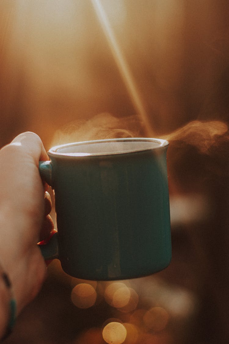 Faceless Person With Mug Of Hot Drink In Sunbeam