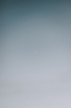 A serene minimalist view of the crescent moon against a twilight sky, conveying peace and solitude.