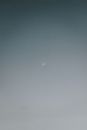 Low angle scenic view of wavy half moon in light gray sky in twilight