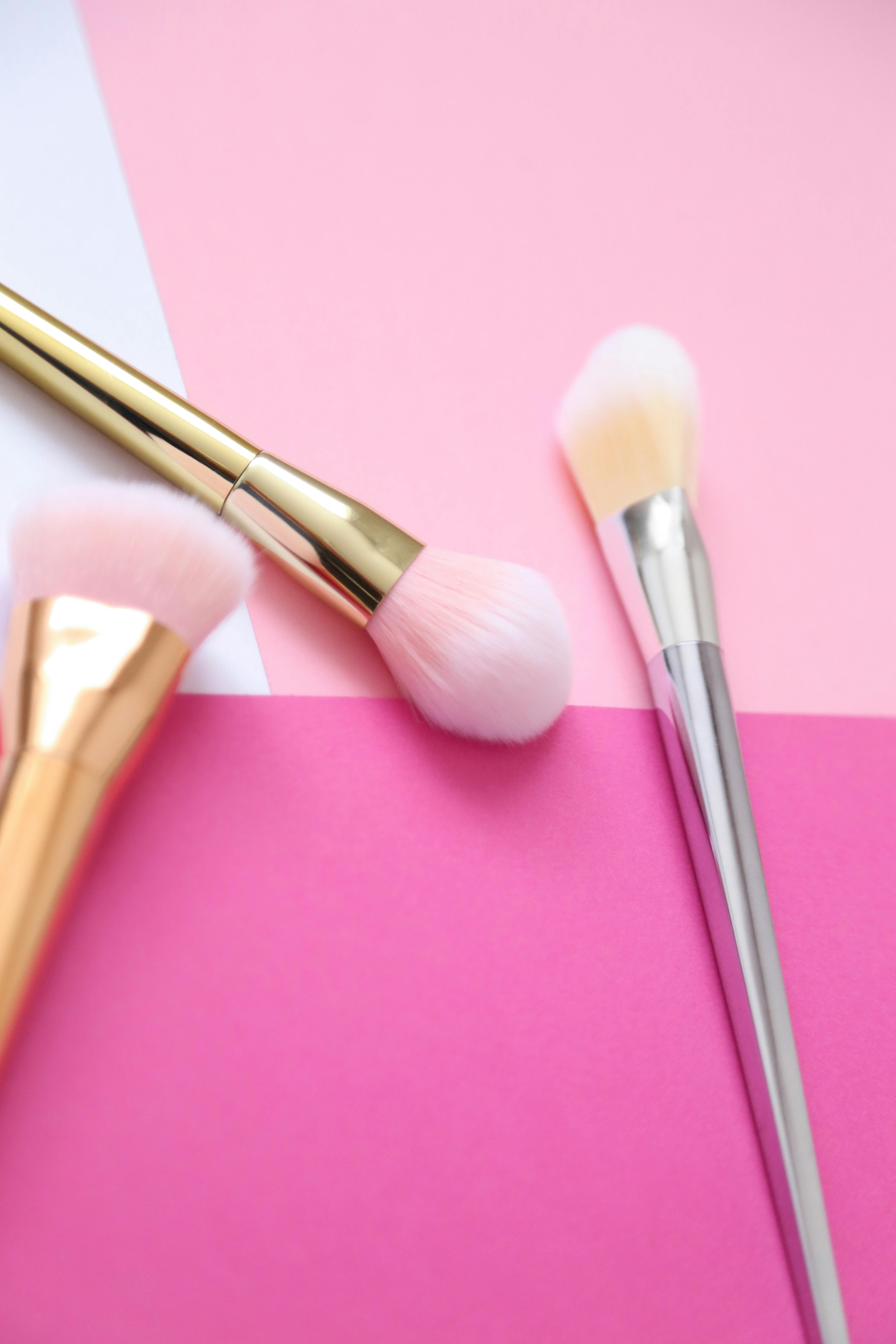 makeup brushes over a pink surface