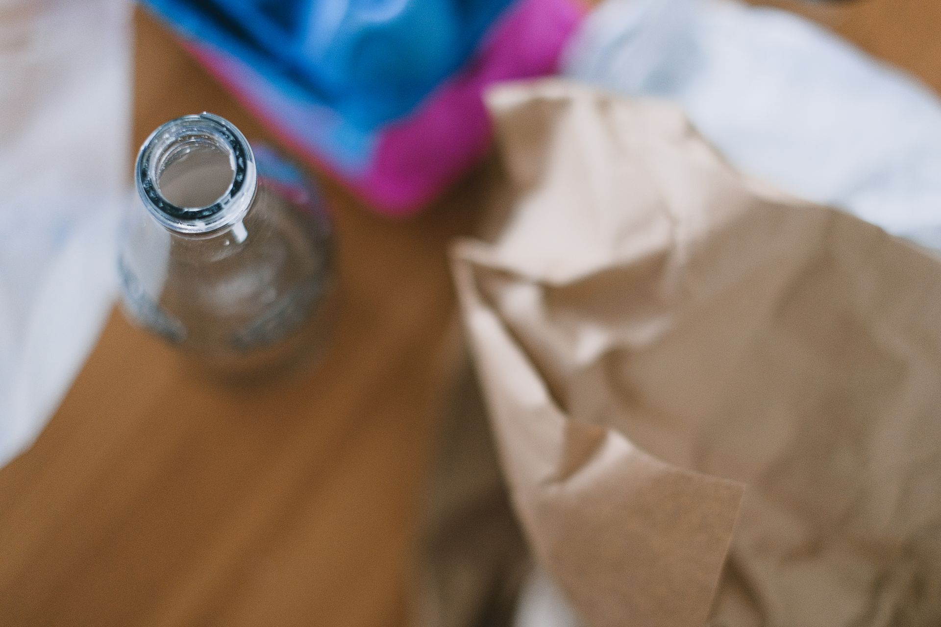 Top view of empty glass bottle with creased paper and egg container prepared for recycling