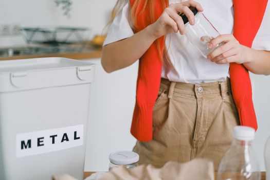Woman unscrewing lid from bottle while sorting trash