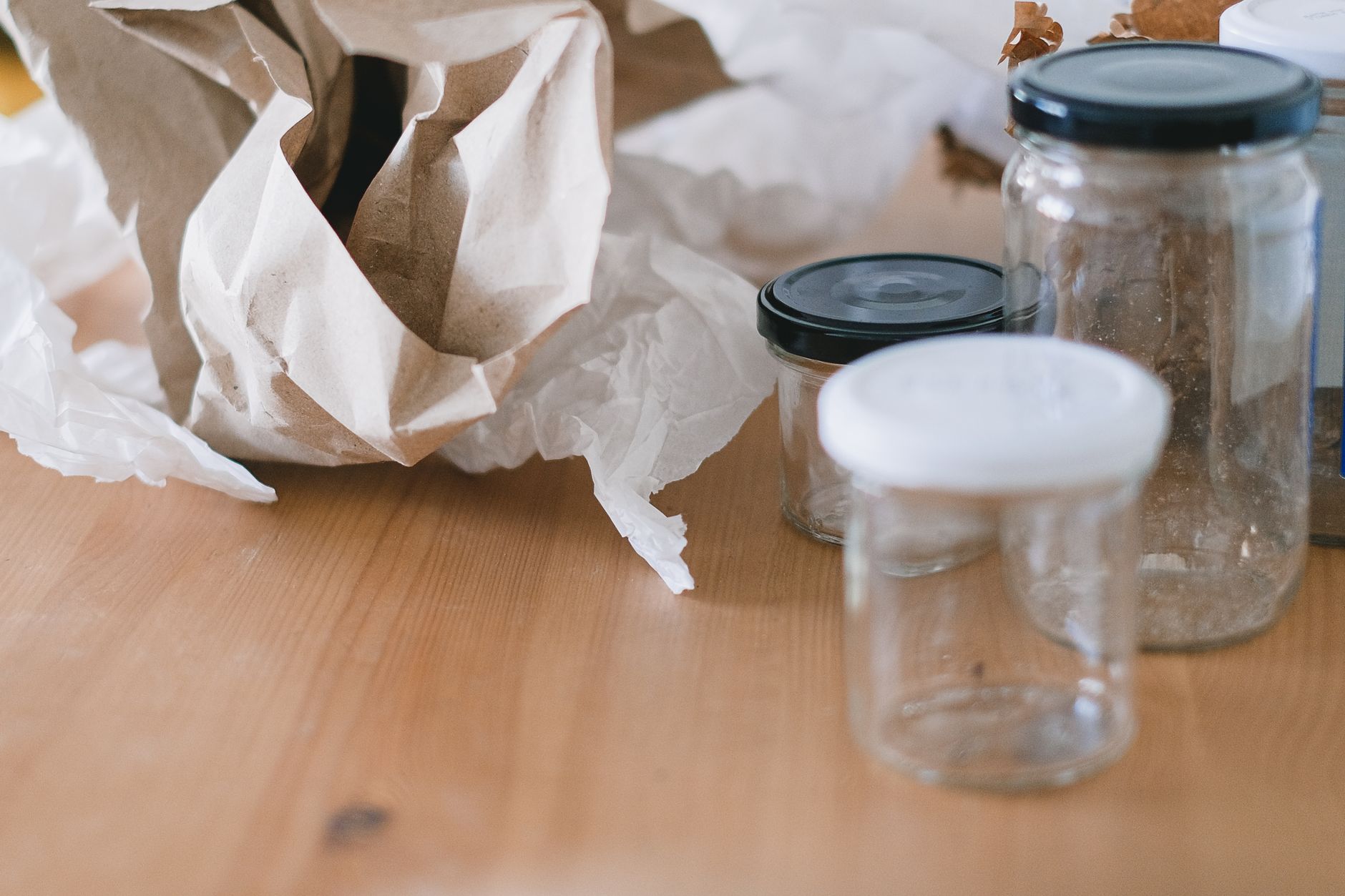 High angle of used empty glass jars with lids placed near creased paper for trash recycling