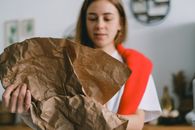 Crop female folding paper while sorting garbage for recycling to reduce pollution of planet