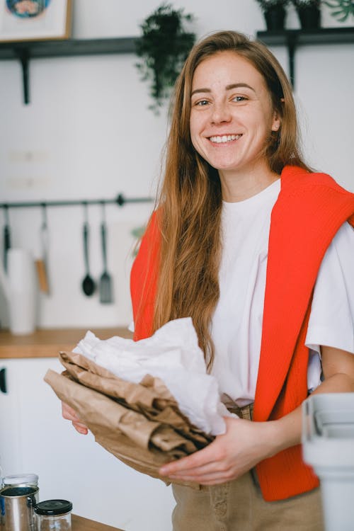 Smiling woman sorting paper litter in kitchen