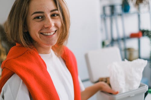 Cheerful woman near rubbish bin in light room