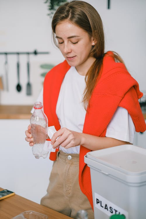 Female disposing plastic bottle into special bin