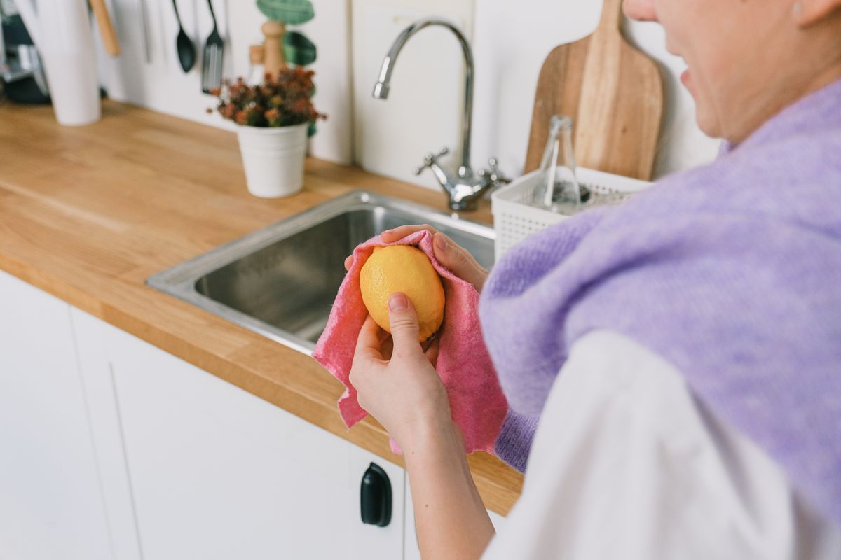 Pessoa manuseando limão fresco dentro de uma cozinha