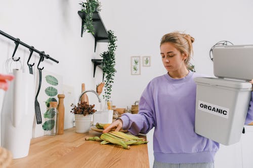 Calm female sorting organic trash in kitchen in light room