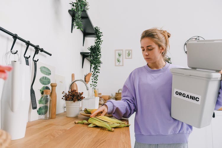 Calm Female Sorting Organic Trash In Kitchen In Light Room