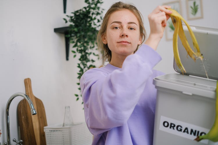 Woman Throwing A Banana Peel Inside A Organic Bin