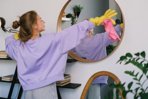 Female in sterile gloves standing with raised arms while cleaning apartment