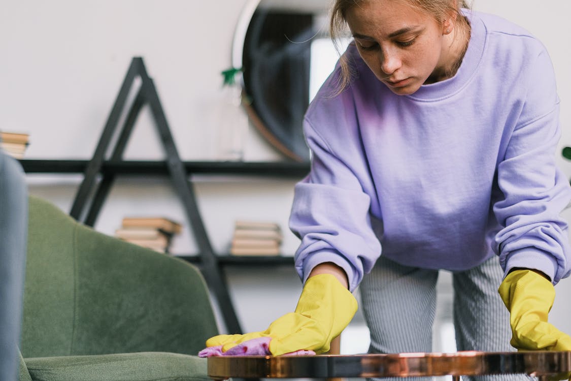 Calm female wiping dusk on table in room