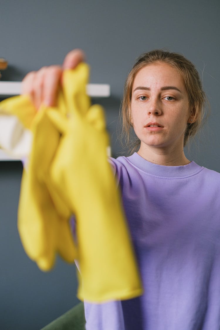 Tired Female Reaching Out Hand With Gloves In Light Room