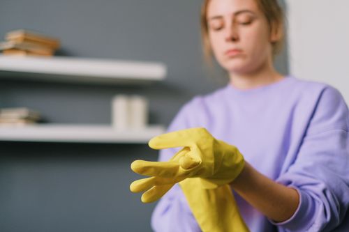 Free Crop blurred female in casual clothes putting on yellow latex gloves in light room in daytime Stock Photo