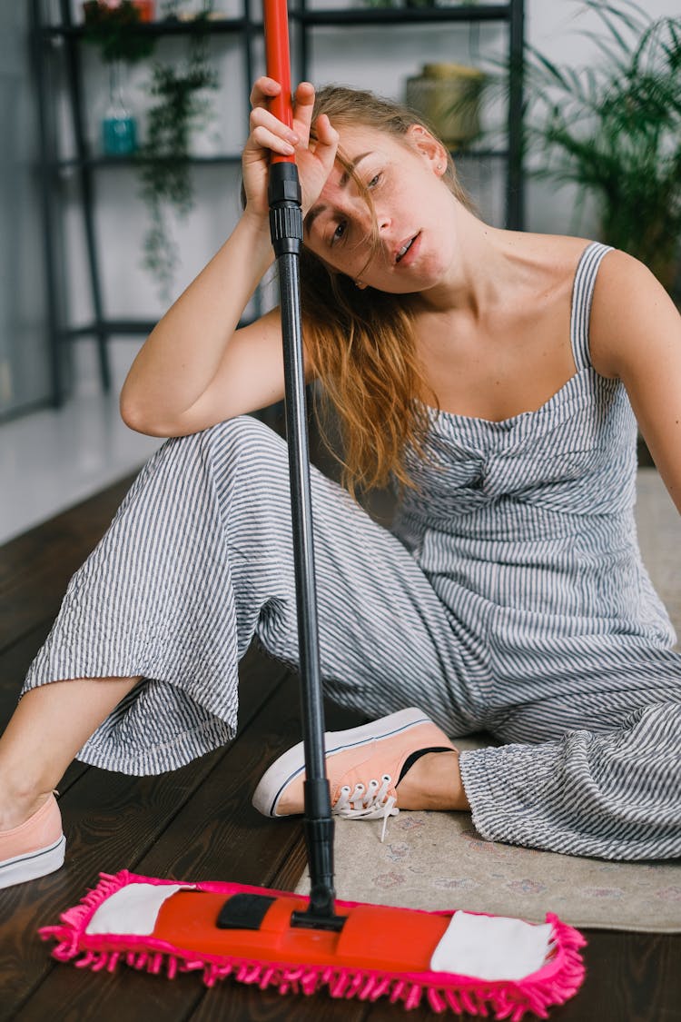 Tired Housewife With Mop Resting On Rug