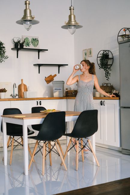 Photo by SHVETS production on Pexels Young lady in casual clothes drinking refreshing beverage while standing near table in light kitchen during breakfast in sunny morning