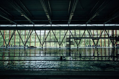 Anonymous swimmer walking on poolside in modern building