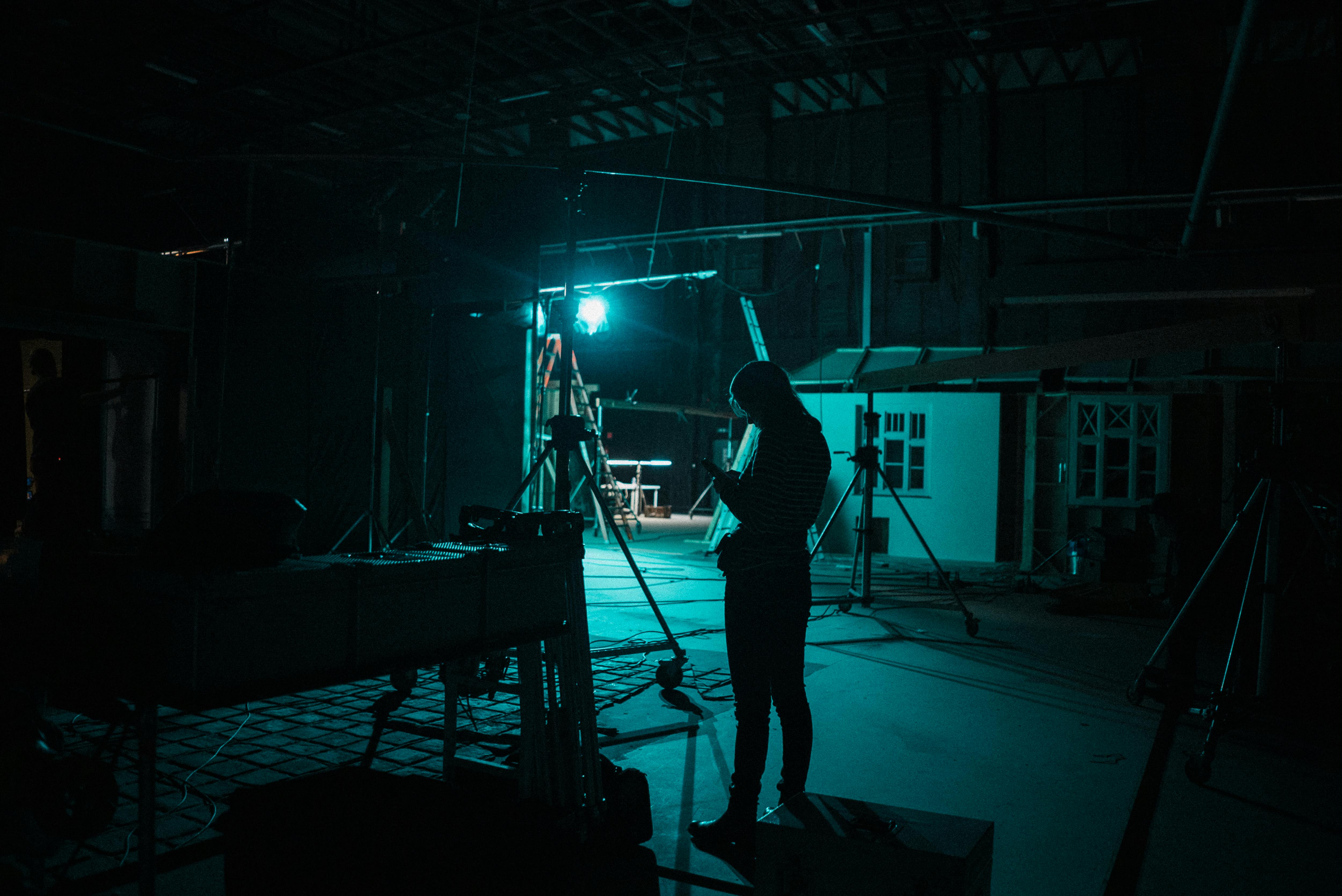 Free A silhouette of a woman on a dimly lit film set in Budapest creates a mysterious atmosphere. Stock Photo