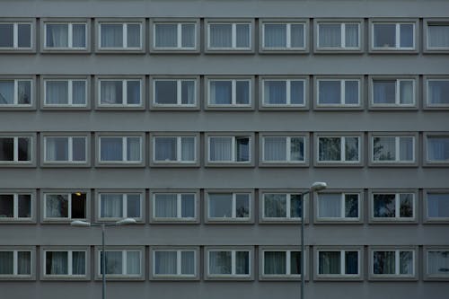 Backdrop of aged multistory building exterior with windows reflecting tree against lamp posts in town