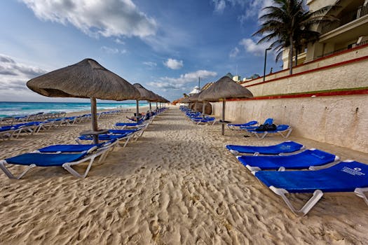 Idyllic tropical beach in Mexico with blue sun loungers and parasols, perfect for relaxation.