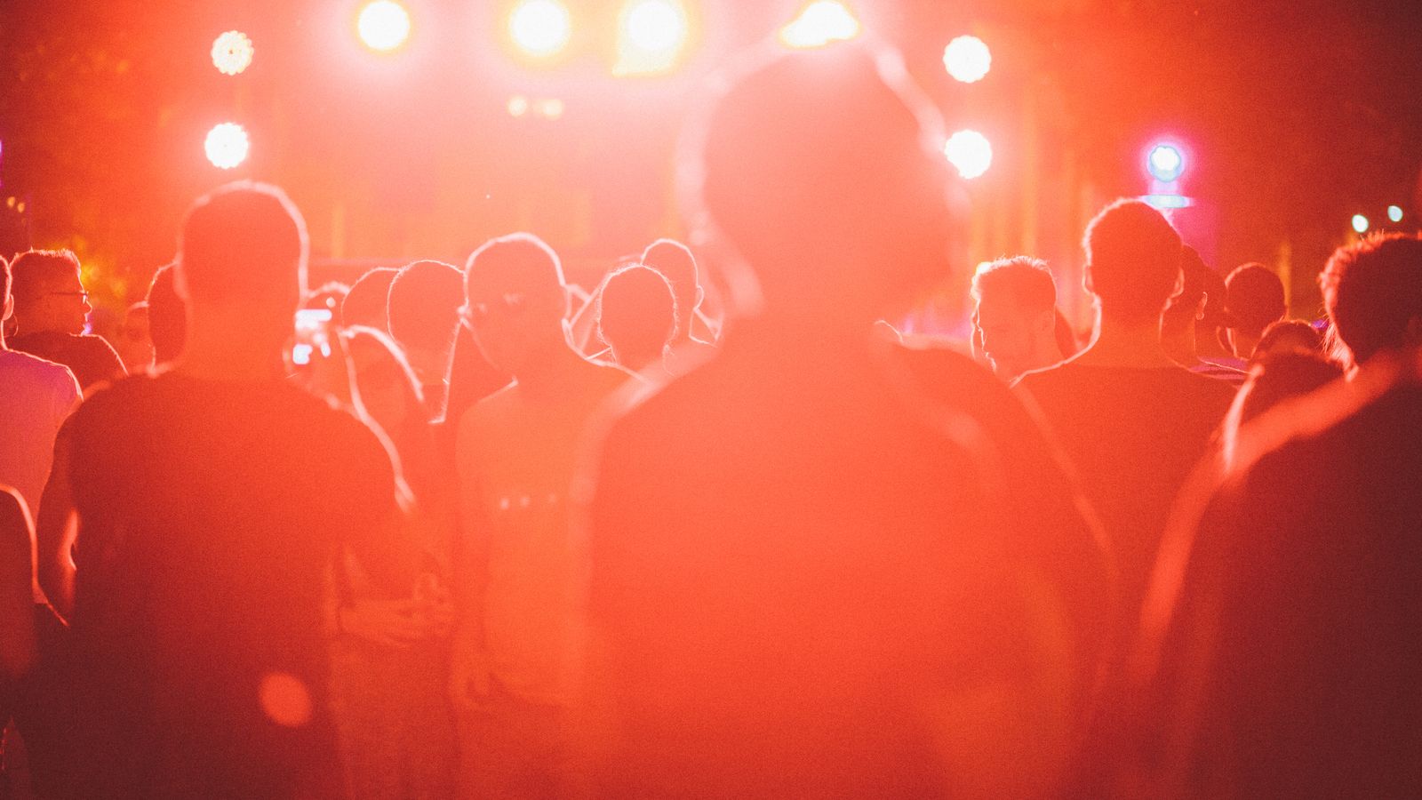 Backlit crowd at an outdoor music festival at dusk