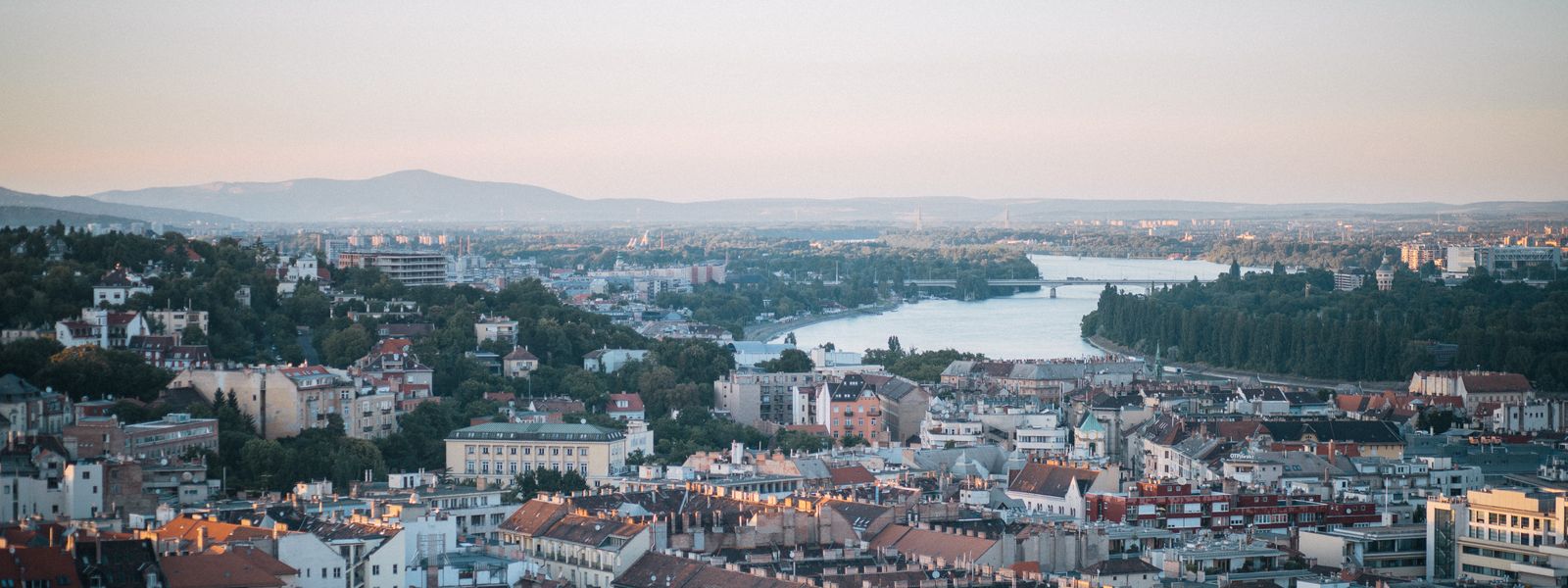 Aerial shot of Budapest with the Danube River and city architecture during sunset.
