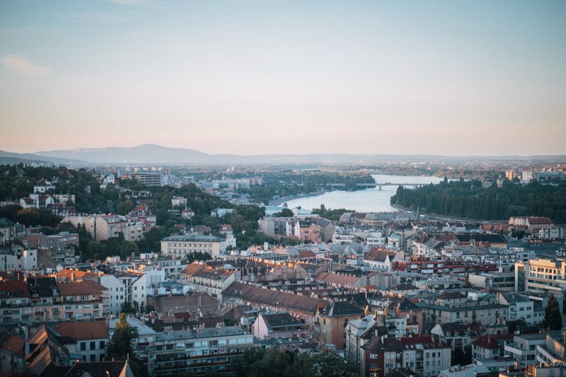 Aerial shot of Budapest with the Danube River and city architecture during sunset.