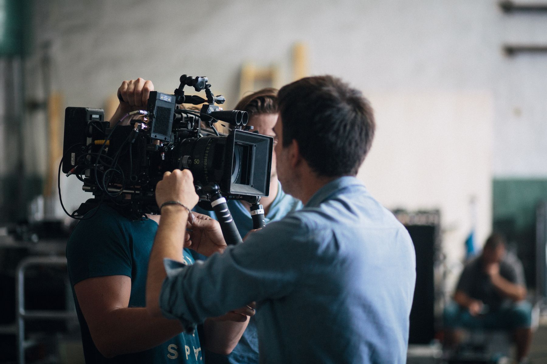 A camera operator and director framing a shot on a cinema camera during an indoor shoot — photo by Bence Szemerey on Pexels