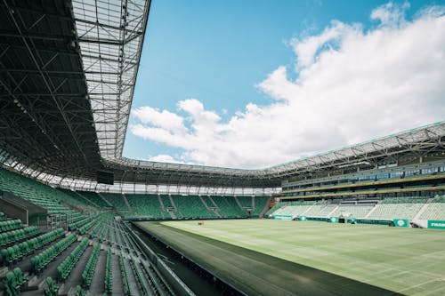 Green Bleachers on a Sports Stadium Under Blue Sky