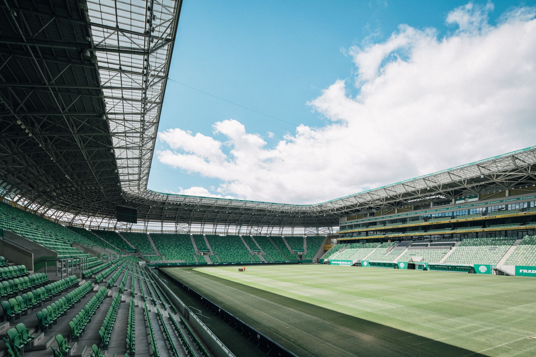 View of a modern stadium in Budapest, Hungary, showcasing green seats and a vast open sky.