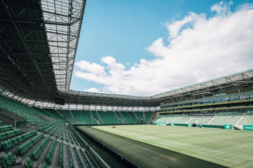 Free View of a modern stadium in Budapest, Hungary, showcasing green seats and a vast open sky. Stock Photo