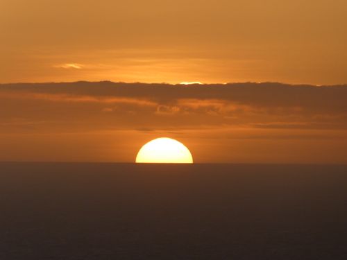 Free A peaceful evening sunset with vibrant orange hues above a calm ocean horizon. Stock Photo