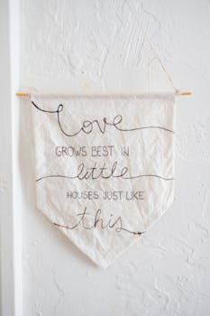 Minimalist wall hanging with positive phrase on white textured background.