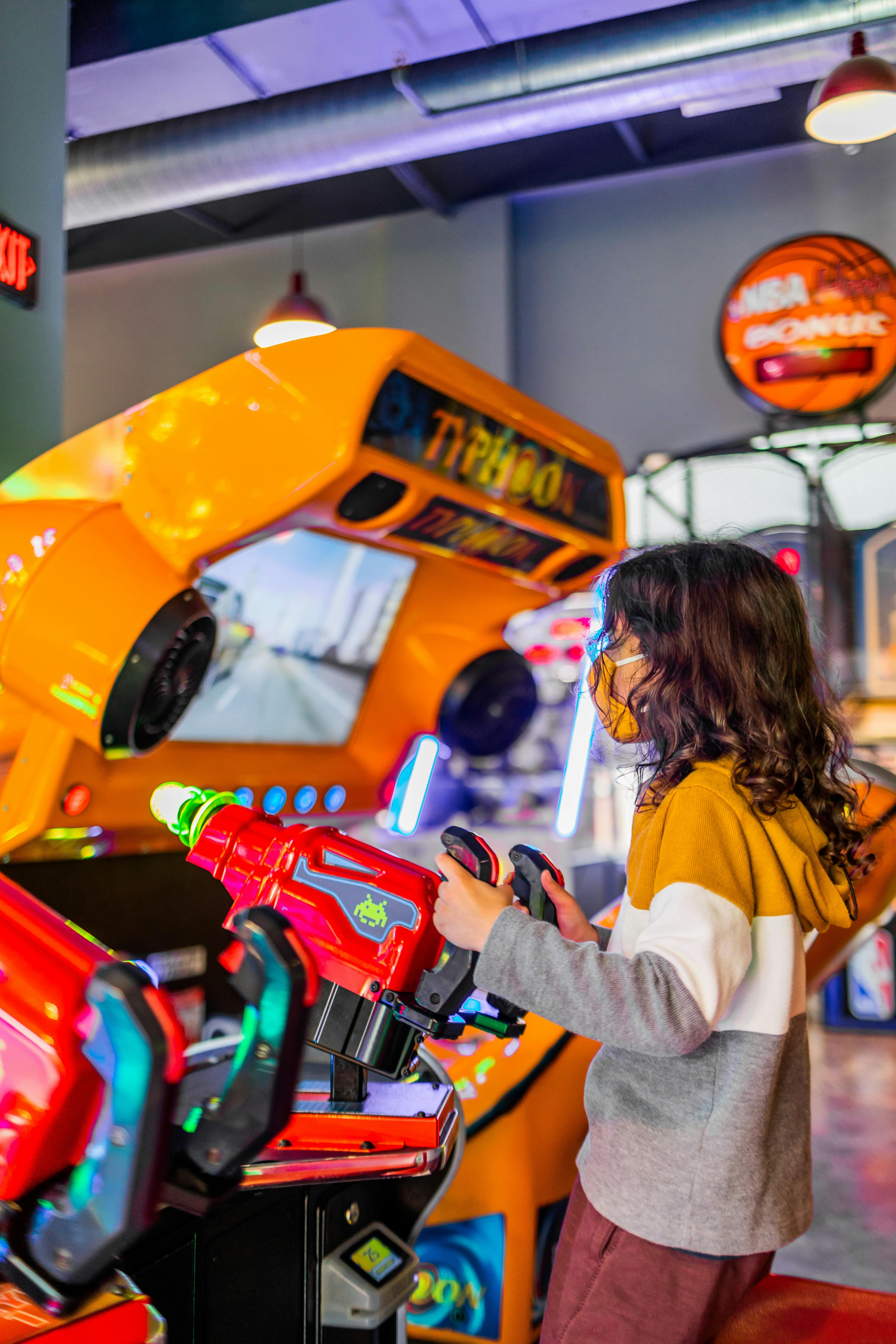 anonymous girl playing shooting game machine in arcade