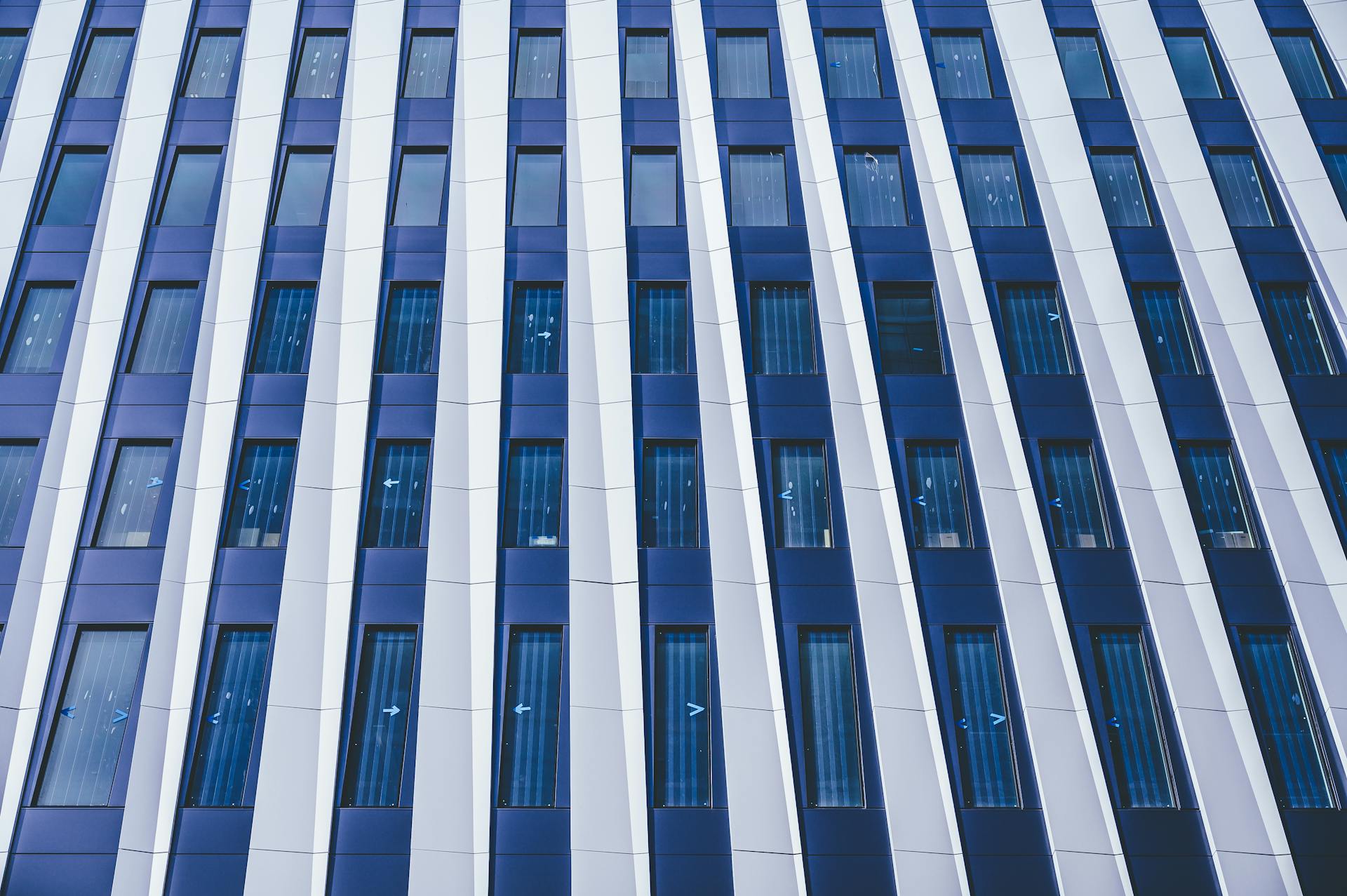 Full frame facade of contemporary multistory building with windows and decorative white panels located on street in financial district of city