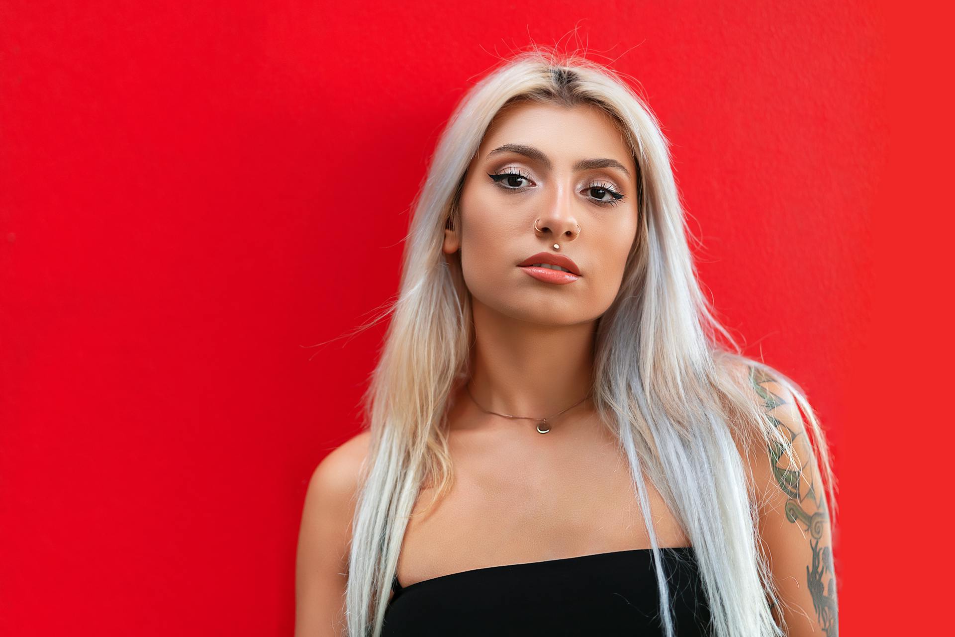 Portrait of a fashionable woman with platinum blonde hair and a bold red background, emphasizing modern style.