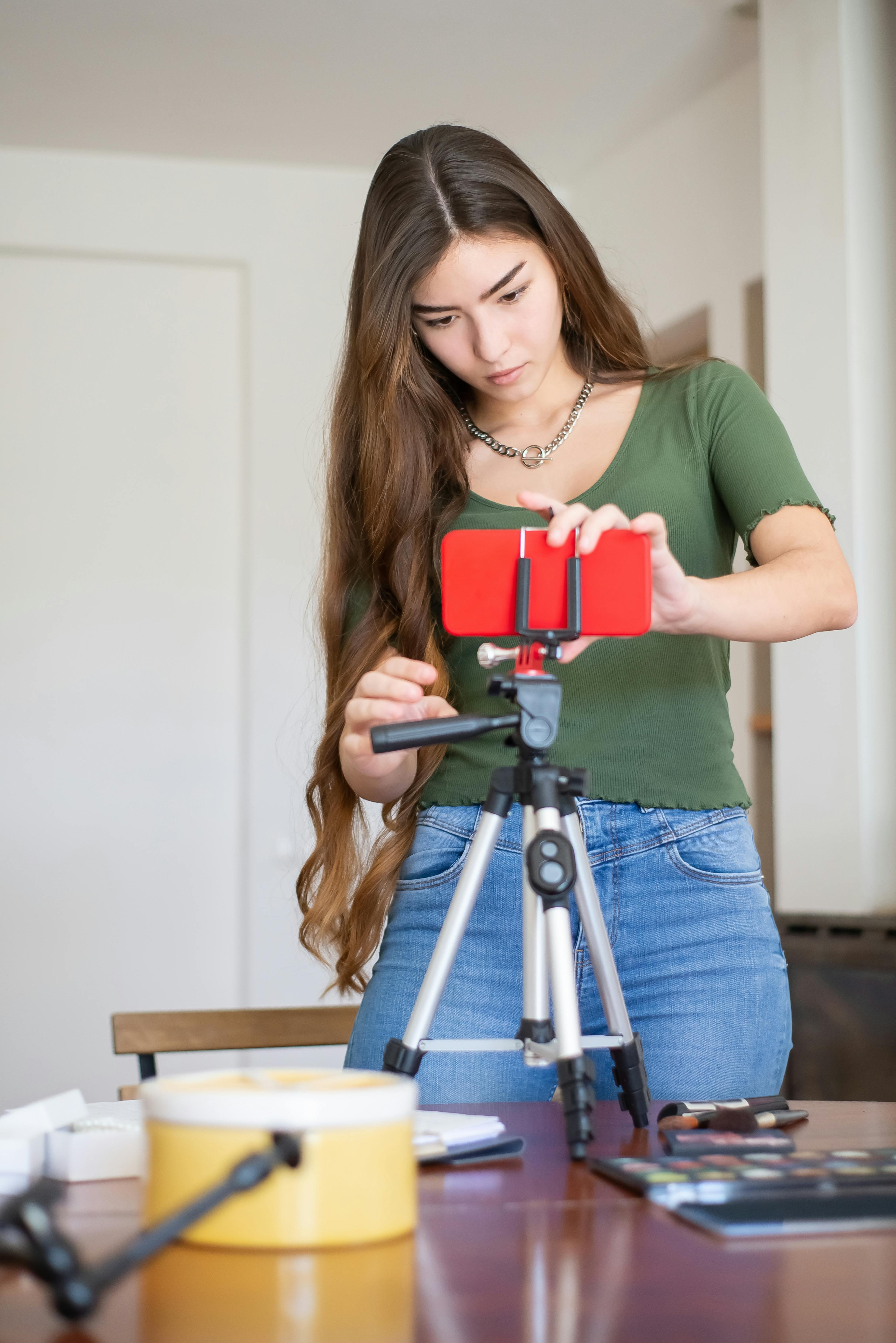 woman in green t shirt setting up the smartphone on the black tripod